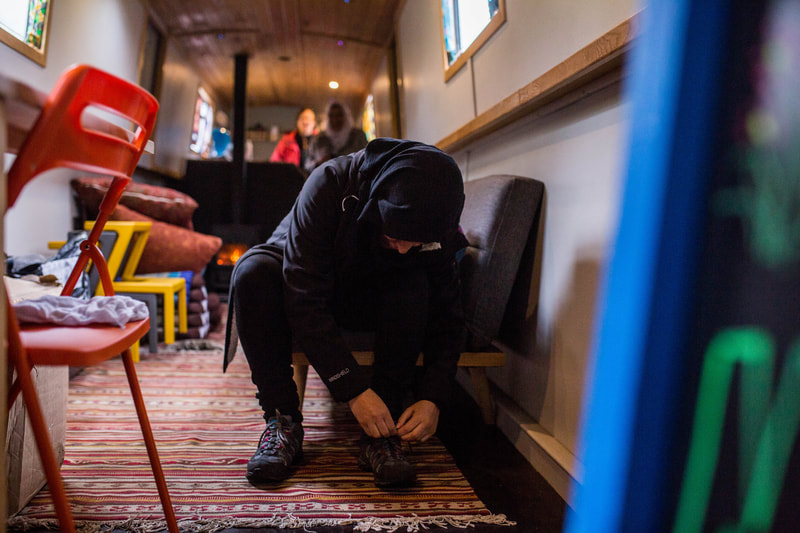 a woman ties her boots inside a narrow boat