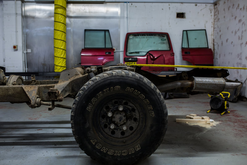a large land rover wheel and stripped down chassie surrounded by land rover parts